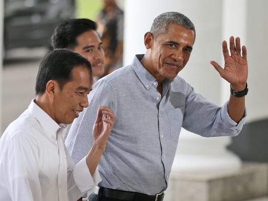 Obama waves to reporters as he walks with Indonesian