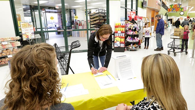 Tina Ellingson fills out an entry form Wednesday at Festival Foods in Fond du Lac for the Pack the Pantry Charity Event. Action Reporter Media staffers Sam Gudex, left, and Kristin Magruder helped shoppers at the in-store booth.