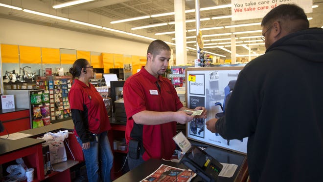 Office Depot OfficeMax logistics specialist Christo Martinez helps a customer at the register on Nov. 24. Farmington is one of two local municipalities that is considering raising its gross receipts tax rate.