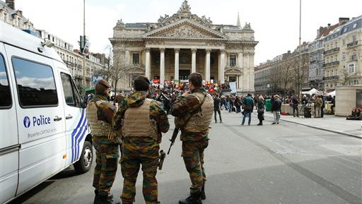 Belgian soldiers stand guard next to one of the memorials to the victims of the recent Brussels attacks, at the Place de la Bourse in Brussels, Sunday, March, 27, 2016. In a sign of the tensions in the Belgian capital with security services under pressure, Belgium's Interior Minister Jan Jambon appealed to residents not to march Sunday in Brussels in solidarity with the victims. (AP Photo/Alastair Grant)