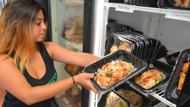 Joseline Sanchez stocks refrigerated coolers with pre-cooked meals at Fia’s Fresh Meals on Wickham Road in Melbourne.