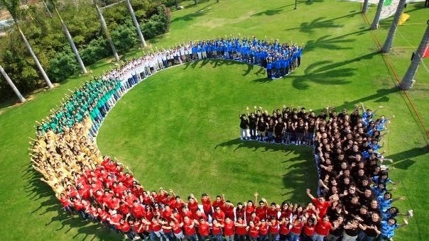 People standing in the shape of the Google logo as seen from above.