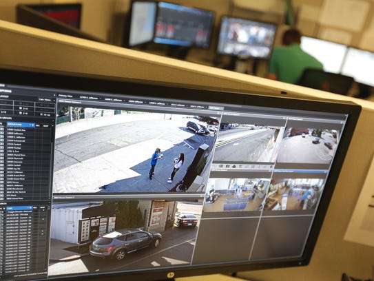 A crime analyst monitors video screens in the real
