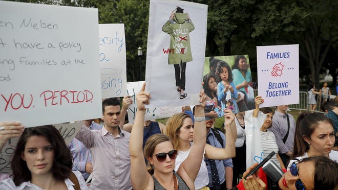 Emily Knobbe, center, holds up a sign during a demonstration opposed to the White House policy that separated more than 2,300 children from their parents over the past several weeks in front of the White House in Washington, Thursday, June 21, 2018. (AP Photo/Pablo Martinez Monsivais)