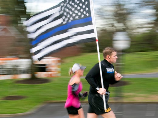 A runner carries a flag along Neyland Dr. in the first