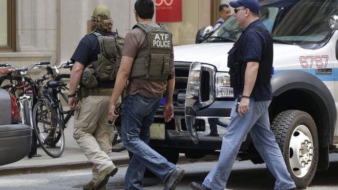 Bureau of Alcohol, Tobacco, Firearms and Explosives agents and Chicago police are seen outside a downtown high-rise office building following a shooting inside the building Thursday, July 31, 2014, in Chicago. Police said a demoted worker shot and critically injured his company's CEO before fatally shooting himself. (AP Photo/M. Spencer Green)