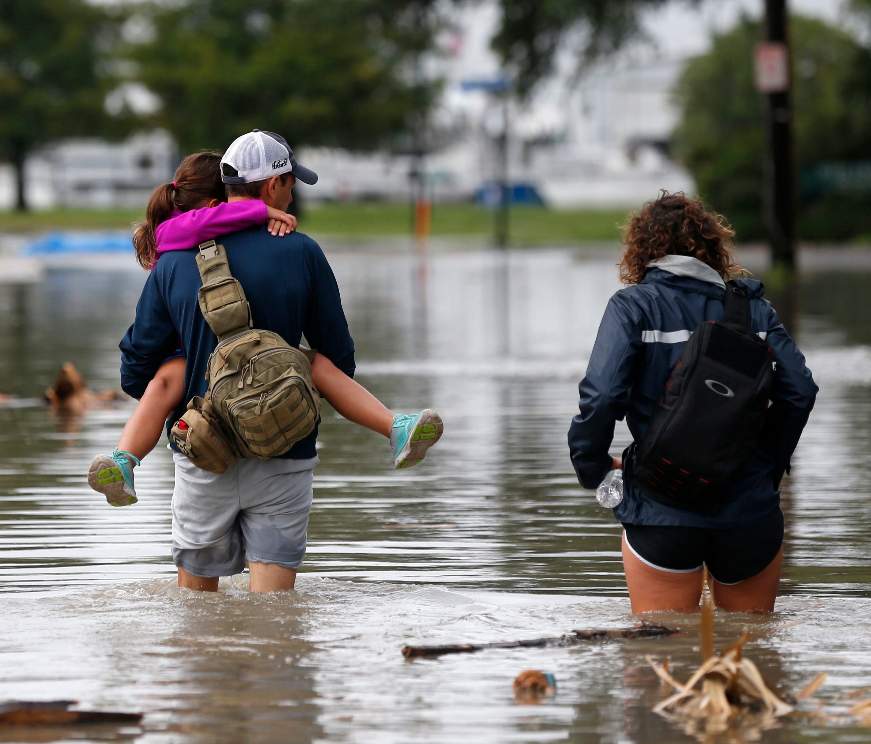 Don Noel carries his daughter Alexis, 8, with his wife Lauren, right as they walk through a flooded roadway to check on their boat in the West End section of New Orleans.