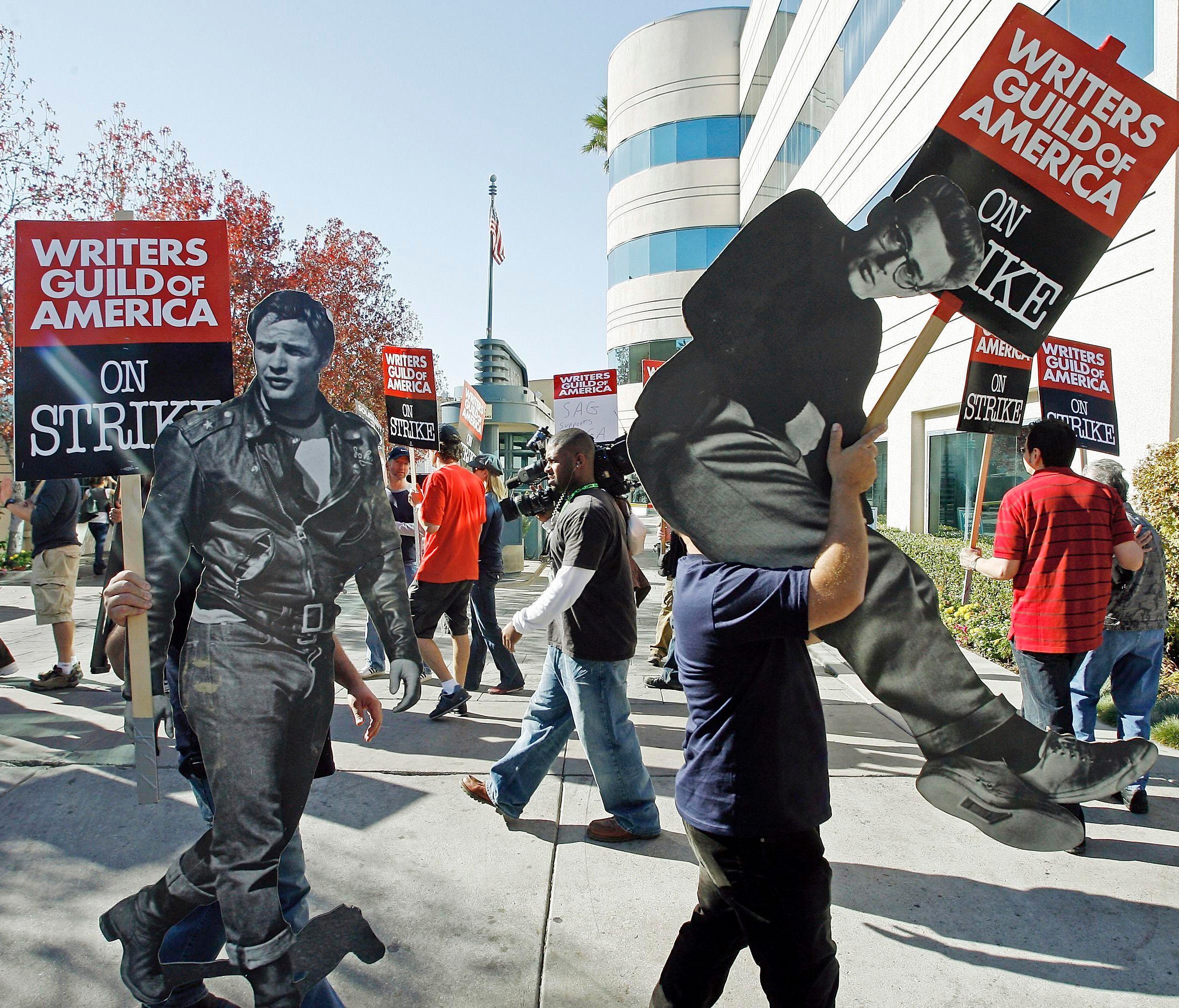 Striking writers in November 2007, carrying life-sized photos of legendary actors, Marlon Brando, left, and James Dean outside Raleigh Studios in Los Angeles.