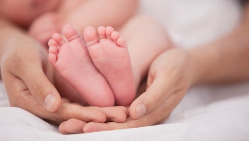 A stock image of hands holding a baby's feet.