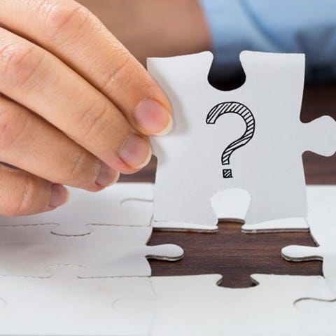 A person holding up a puzzle piece with a question