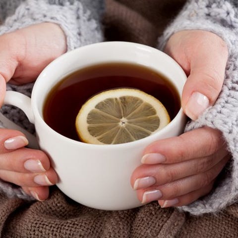 A lady's hands holding a cup of tea with a whole...