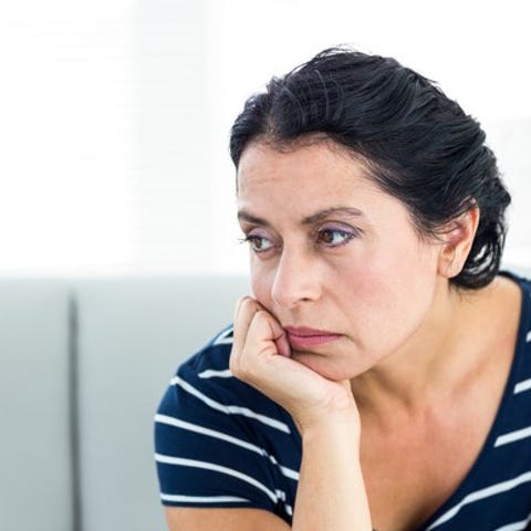 A woman, seated, looks away unhappily with her chi