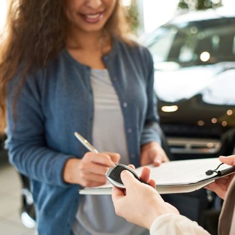 Woman signing paperwork at car dealership.