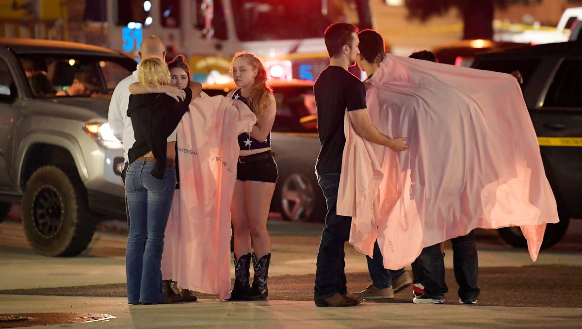 People comfort each other as they stand near the scene Thursday in Thousand Oaks, Calif. where a gunman opened fire Wednesday inside a country dance bar crowded with hundreds of people on "college night."