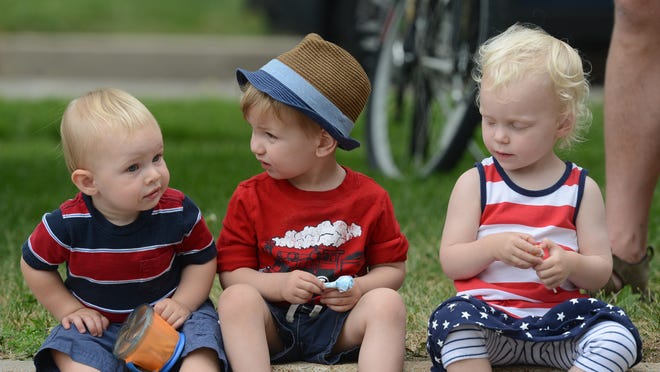From left, Benjamin Toombs, 1, Gus Reedy, 2, and Sloane Worcester, 2, sit on a curb to watch the Independence Day Parade along Mountain Ave. in Fort Collins in 2014.
