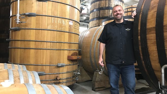 Former MSU long snapper Tony Grant stands between oak barrels on the "sour beer" side of the Northern United Brewing Company headquarters Tuesday in Dexter.