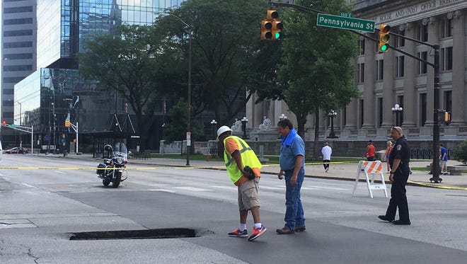 Workers inspect a sinkhole that opened up before 4 p.m. July 4, at the intersection of Ohio St. and Pennsylvania Ave.
