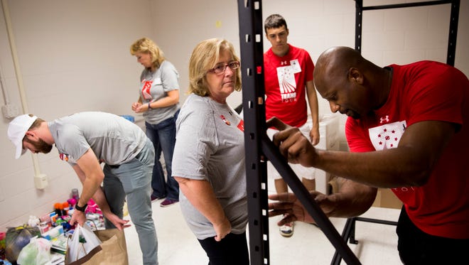 Athletic director with the Boys & Girls Club Ron Strong, from right, Cal Ripken, Sr. Foundation volunteer Colton Rossow and UnitedHealthcare volunteer Cheryl Seitz construct a metal shelf to be used for pantry storage, while other volunteers organize donated items at Immokalee High School on Tuesday, May 23, 2017, in Immokalee, Fla.