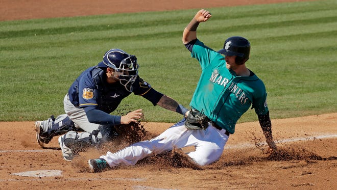 Seattle Mariners' Mitch Haniger is tagged out at home by Brewers catcher Manny Pina during a spring training baseball game Thursday, March 2, 2017, in Peoria, Ariz.