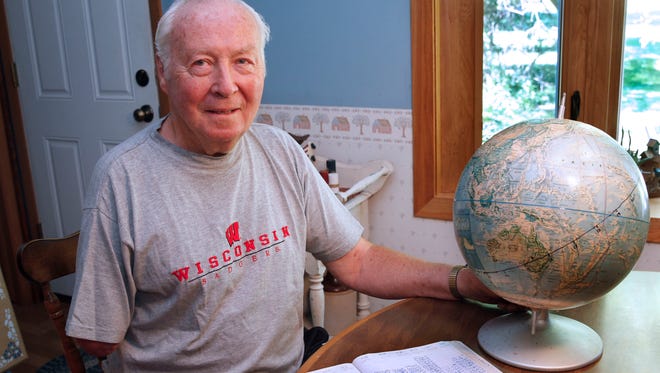 Tom Krueger with a log of his miles and world globe at his Brown Deer home. Krueger has been walking a few miles a day since he retired in 1994 and he maps his progress with a globe in tiny increments. He's nearly halfway around the globe for the second time.