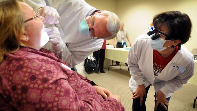 Dr. Bill Renner and Susan Birdsall from Waukesha County Technical College check the teeth on a client at a previous year's Touched Twice Lake Country free clinic. This year's event is planned for Oct. 14 at Oakwood Church.
