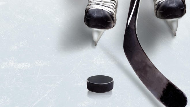 Ice hockey game showing stick on puck with part of player's skates on ice and copy space.