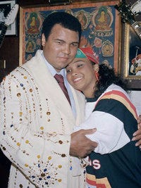 Former heavyweight champion Muhammad Ali gets a hug from his daughter Maryum "May May" Ali at New York's Hard Rock Cafe, May 12, 1988. Ali donated the robe he's wearing, given to him by Elvis Presley and worn at many of his title fights, to a display of memorabilia at the club.