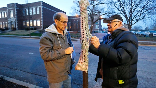 Bill Evers, left, and Steve Green wrap sweaters around young trees along Columbia Street near Morton Community Center Tuesday, December 8, 2015, in West Lafayette. Sixteen volunteers with West Lafayette Tree Friends "yarn bombed" trees with 70 sweaters near Chauncey Village. Along with each sweater, a note was also clipped to the trees with a simple message. It is hoped the sweaters and messages will deter vandalism to the trees.
