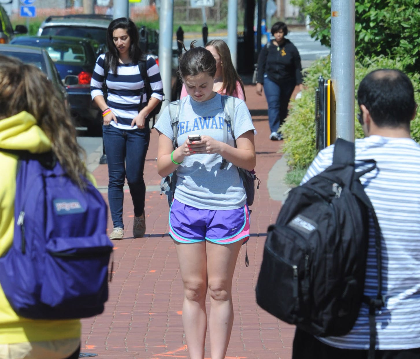 A Newark, Del. pedestrian crosses the street while using her phone on May 11, 2012.