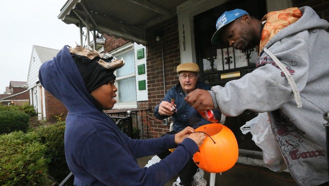 Zanaija McIntrye of Detroit goes trick or treating on Alma St. in Detroit and gets candy from Nick DiNunzio and Charles Fuqua on Halloween last year.