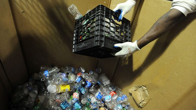 
A Marion Correctional Institution inmate scoops up a crateful of plastic bottles to be placed in a compactor at the MCI Recycling Processing Center. 
