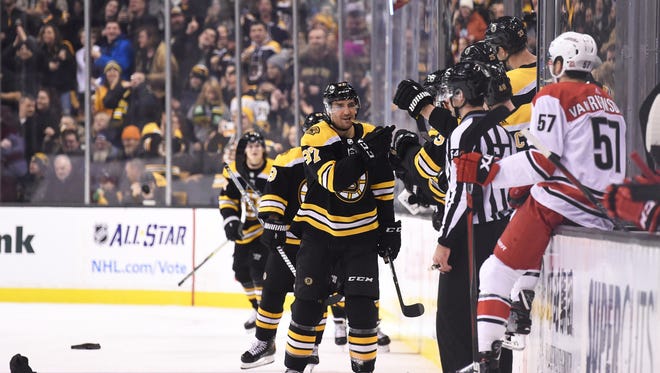 Boston Bruins center Patrice Bergeron (37) celebrates with teammates on the bench after scoring his third goal of the game during the second period against the Carolina Hurricanes at TD Garden.