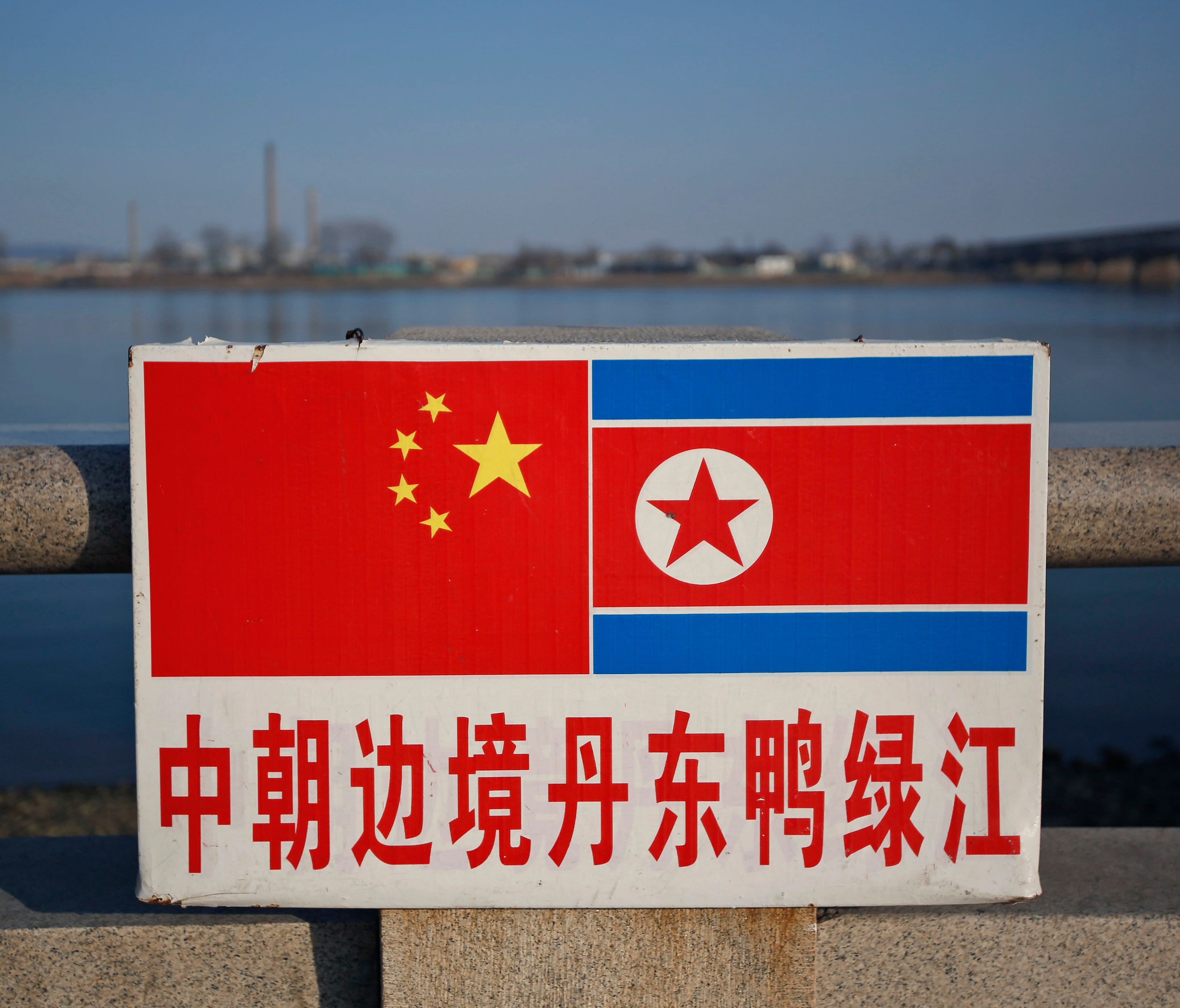 The Chinese and North Korean national flags are seen on a sign along the Yalu River where across is the North Korean town of Sinuiju in Dandong, Liaoning Province, China, April 7,  2013 (reissued Sept. 29, 2017).