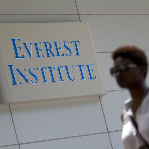 A woman walks past an Everest Institute sign in...