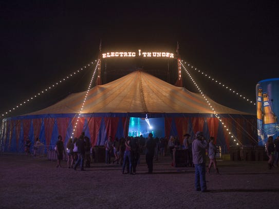 Festival goers walk around the electric thunder tent