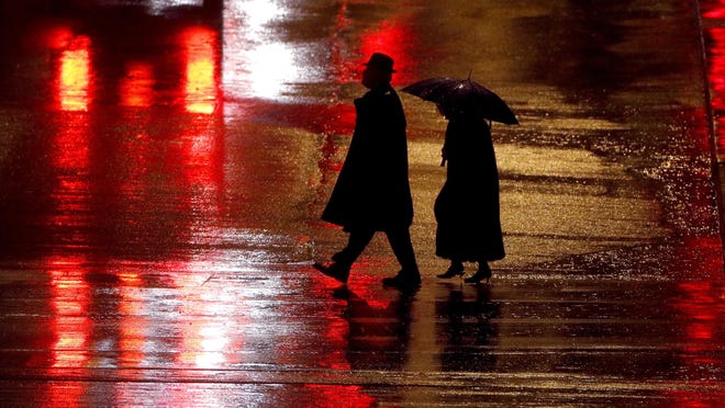 In this Dec. 26, 2018 file photo, pedestrians are silhouetted against wet pavement as they walk in the Country Club Plaza shopping district in Kansas City, Mo.