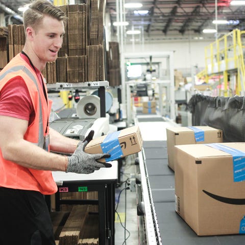 An Amazon warehouse worker placing a box on a...
