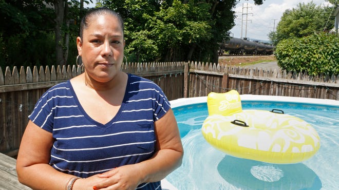 The home of Doris Quinones is less than 100 feet away from the CSX railroad tracks, on which as many as four oil trains pass by every day, not to mention freight trains carrying other hazardous chemicals. Quinones is shown in her yard as an oil train passes July 31 in Haverstraw.