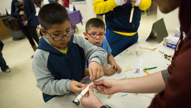 Oli Acevedo, 8, left, and his brother Kiko Acevedo, 6, right, learn to construct a miniature catapult from popsicle sticks and plastic spoons Thursday, February 23, 2017, from Jose Rodriguez a chemical and materials engineering major from New Mexico State University. The activity was part of Engineering Day at the Las Cruces Museum of Nature and Science.