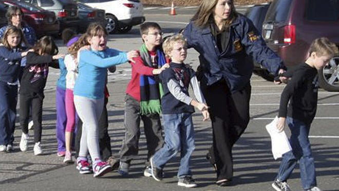 In this photo provided by the Newtown Bee, Connecticut State Police lead children from the Sandy Hook Elementary School in Newtown, Conn., following a reported shooting there Friday, Dec. 14, 2012.  (AP Photo/Newtown Bee, Shannon Hicks)  MANDATORY CREDIT
