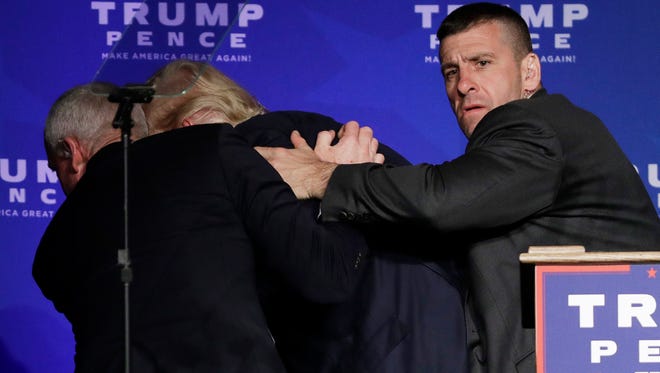 Secret Service agents rush Republican presidential candidate Donald Trump off the stage during a campaign rally in Reno, Nev., on Saturday, Nov. 5, 2016. He returned to the podium afterwards.