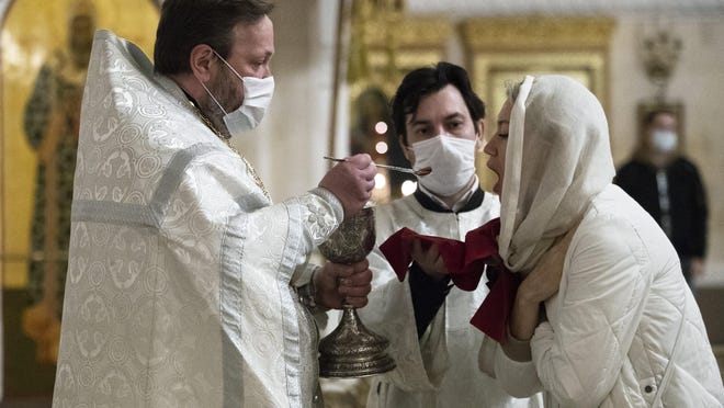 An orthodox priest wearing a face mask to protect against coronavirus distributes Holy Communion during a service at the Christ the Savior Cathedral in Moscow, Russia, Tuesday, June 2, 2020. Churches in Moscow reopen to believers after a two-month lockdown imposed to control the spread of the coronavirus.