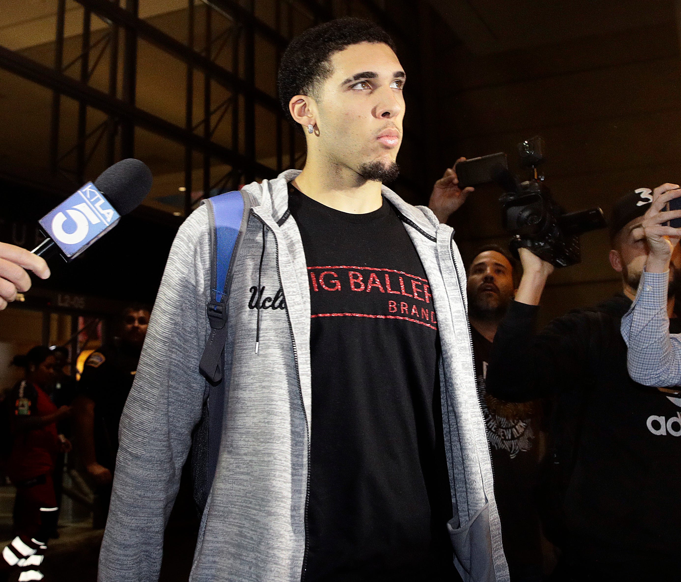 UCLA basketball player LiAngelo Ball is surrounded by reporters and photographers as he leaves Los Angeles International Airport on Tuesday, Nov. 14, 2017, in Los Angeles. Three UCLA basketball players–Ball, Jalen Hill and Cody Riley–detained in Chin