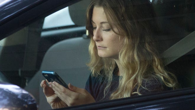 A driver uses her mobile phone while sitting in traffic Wednesday, June 22, 2016, in Sacramento, Calif.
