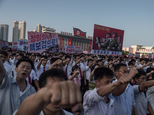 People wave banners and shout slogans as they attend