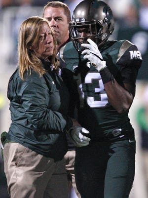 MSU cornerback Vayante Copeland walks off the field with a kneck injury with the help of MSU doctor Sally Nogle during a Sept. 12 game against Oregon at Spartan Stadium. Seventeen years earlier, Amp Campell suffered a similar injury.