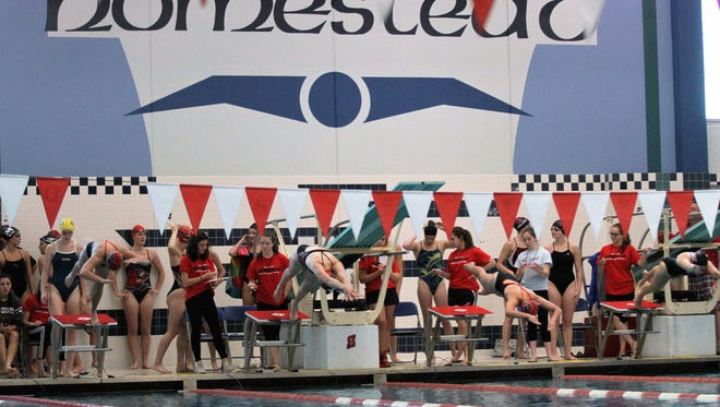 Swimmers dive off the starting blocks during the start of the 50 yard freestyle race during the Girls Varsity Swim Invitational at Homestead High School on Oct. 8.