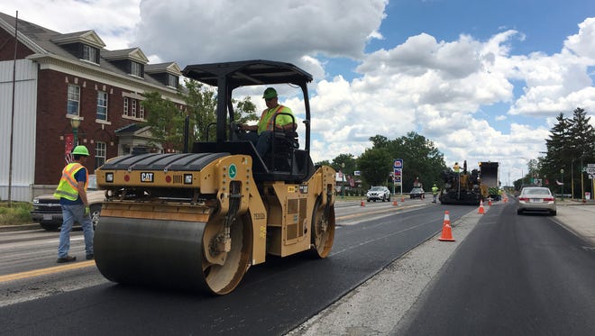Construction workers repave U.S. 20 through Woodville on Monday afternoon.