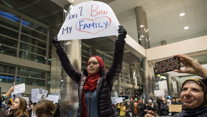 Demonstrators hold signs and chant in the baggage claim area during a protest against President Donald Trump's executive order banning travel to the United States by citizens of several countries Sunday, Jan. 29, 2017, at Detroit Metropolitan Airport.