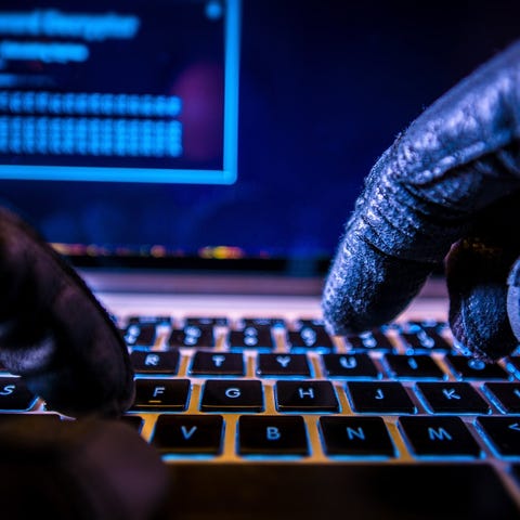 A hacker wearing black gloves who's typing on a ke